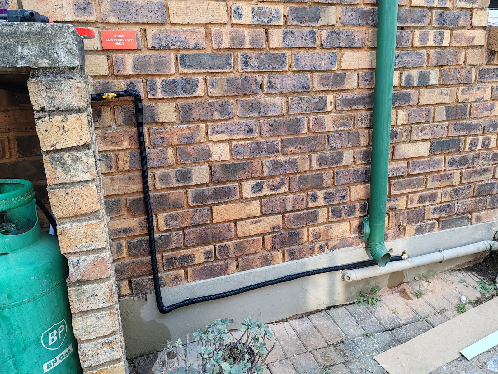 External gas line routed along brick wall with safety shut off valve